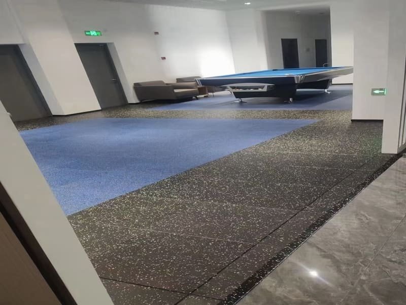 A professional installer checking the levelness of a subfloor before laying rubber flooring